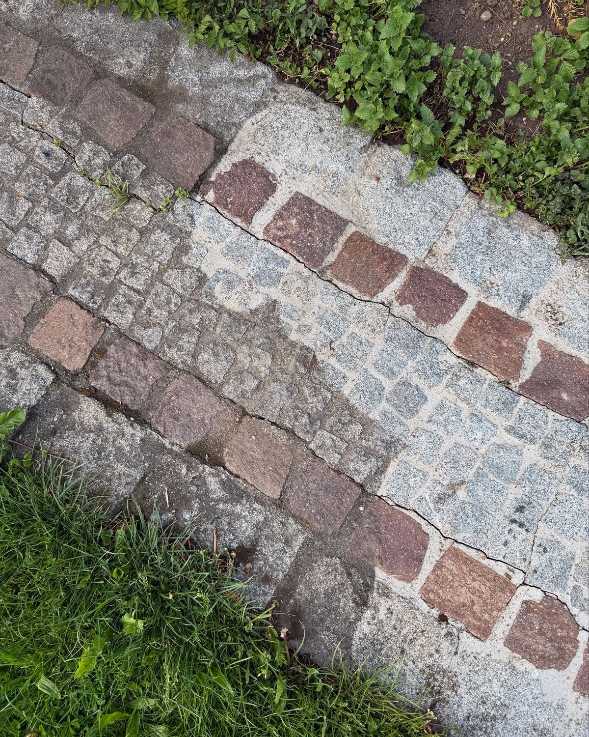 Granitpflaster mit roten Steinen, rechts gereinigt und hell, links noch dunkel verschmutzt